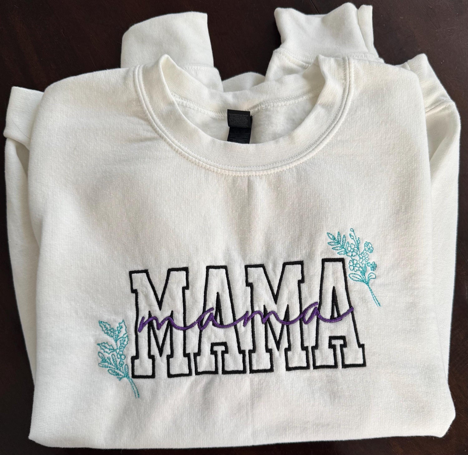 "Mama" embroidered on white sweatshirt with cursive "Mama" written across it. Added birth flowers of children in corners